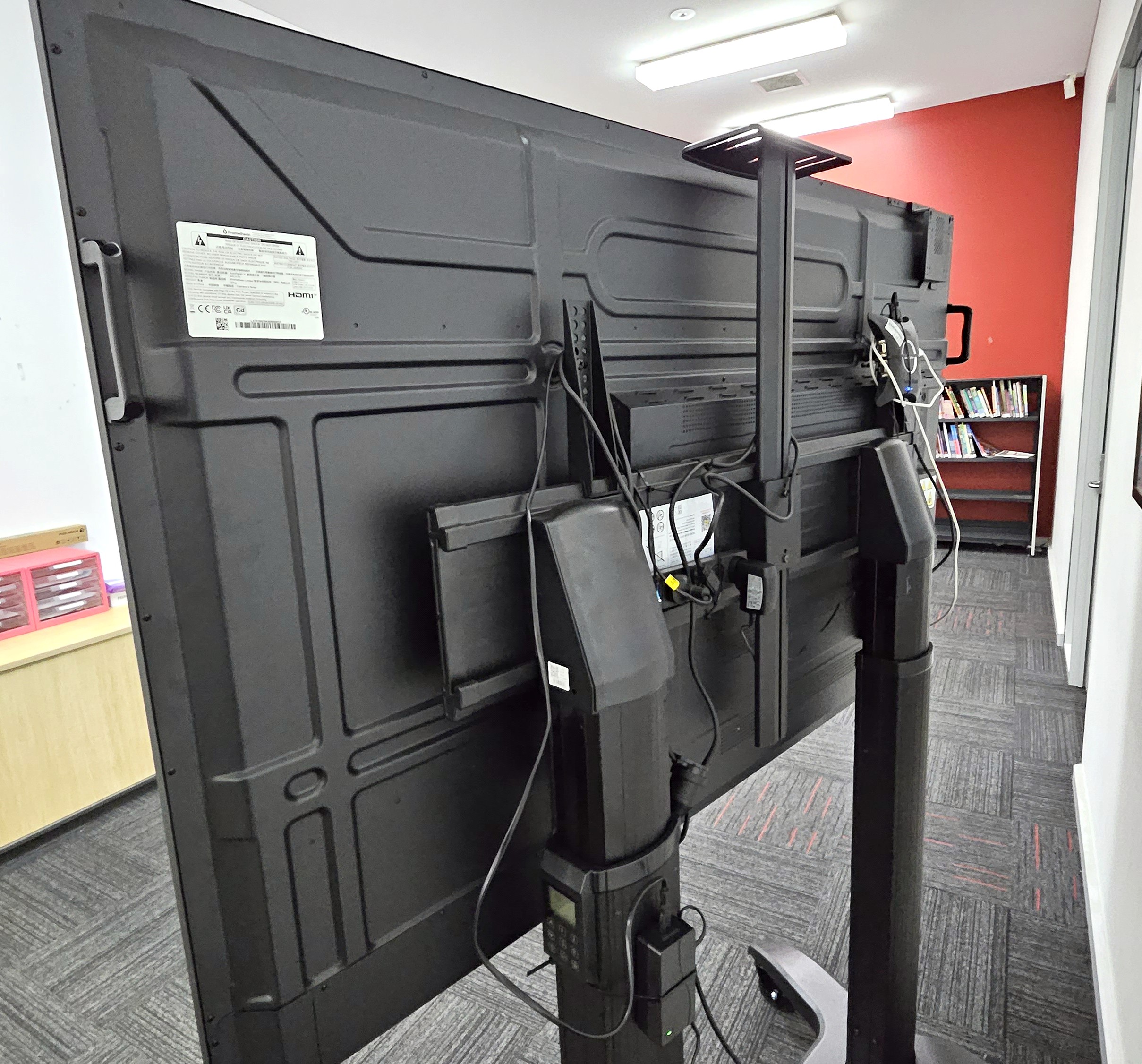 Rear view of an interactive screen on a trolly, with cabling.